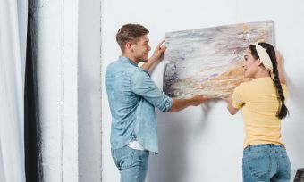 Couple hangs a painting