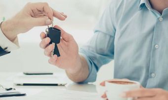 Car sales person handing over key to new owner