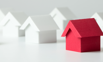 Red model house among white model houses